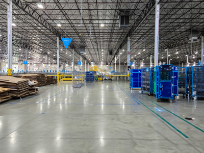 A large grey room with blue trolleys and brown cardboard boxes