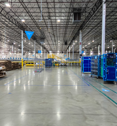 A large grey room with blue trolleys and brown cardboard boxes