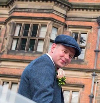 Luke Ashton, a man wearing a grey suit and flat cap