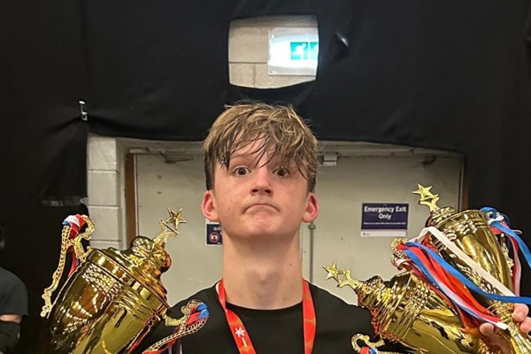 Alex Eastwood holding kickboxing trophies and medals