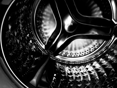 a close up shot of a black and silver tumble dryer drum with geometric dark metal rivets