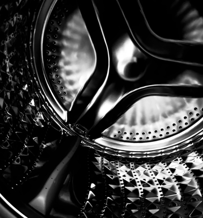 a close up shot of a black and silver tumble dryer drum with geometric dark metal rivets