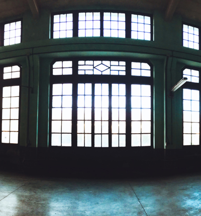 A silhouette of a generic empty industrial warehouse with large black edged glass windows