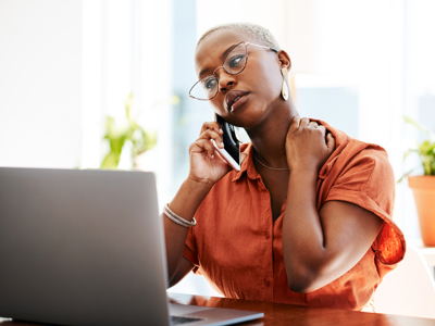 Woman with glasses on her mobile phone, hand on neck