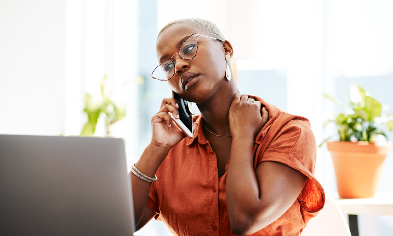 Woman with glasses on her mobile phone, hand on neck