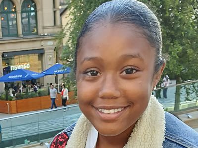 Picture of Mia Shay St Hilaire in a city square wearing a blue denim jacket