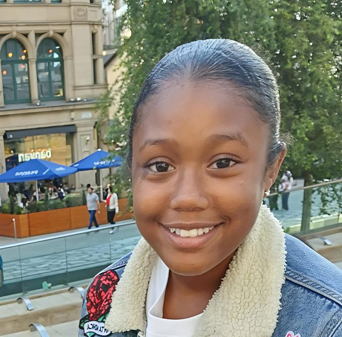 Picture of Mia Shay St Hilaire in a city square wearing a blue denim jacket