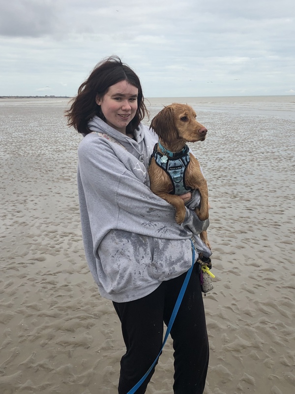 Hannah Aitken on a beach holding a dog