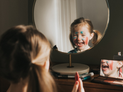 Child looking in mirror in facepaint