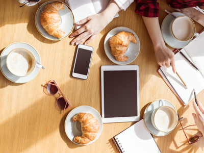 overhead view of young women sitting at coffee break with digital devices, business lunch - stock photo