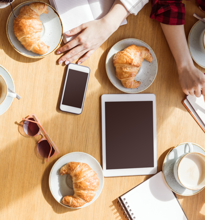 overhead view of young women sitting at coffee break with digital devices, business lunch - stock photo