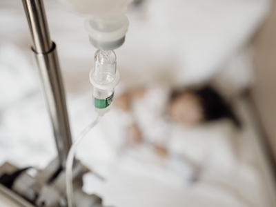 Close-Up View of Saline Drip Hanging on Metal Hook in Hospital Setting