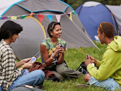 Group Of Young Adults At Campsite Playing Cards