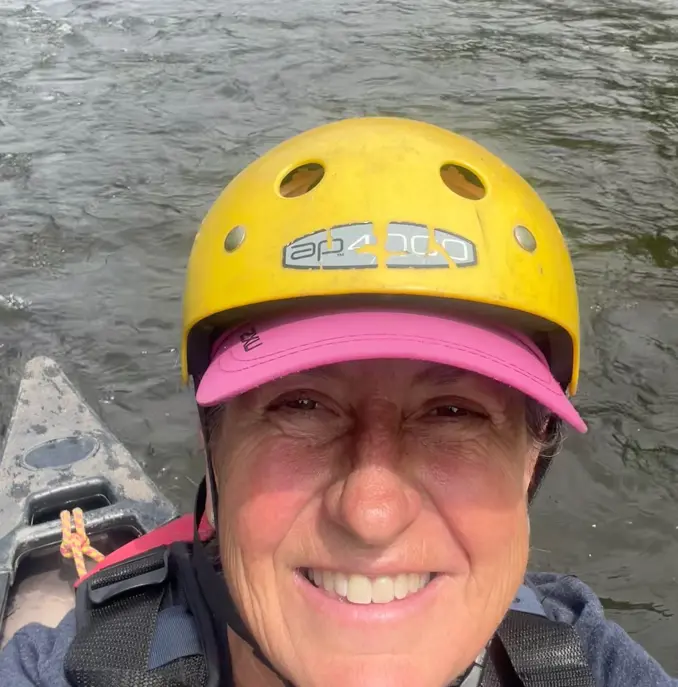 A woman wearing a yellow helmet in front of the river Wye