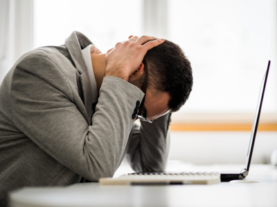 Professional man at laptop with head in hands