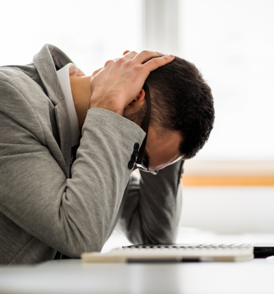 Professional man at laptop with head in hands