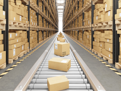 Brown cardboard boxes on a silver conveyor belt next to shelves of brown cardboard boxes