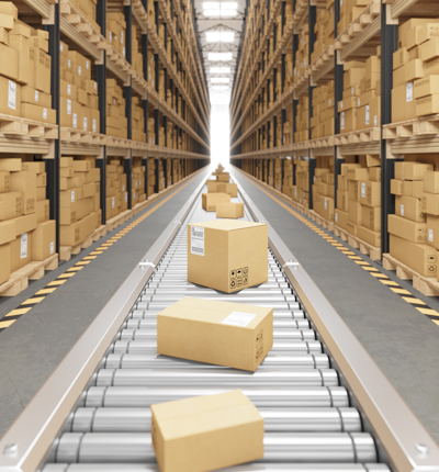 Brown cardboard boxes on a silver conveyor belt next to shelves of brown cardboard boxes