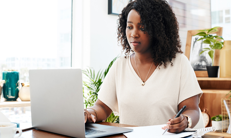 Lady sat in front of laptop holding a pen