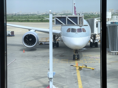 A grey aircraft with the nose pointing at the camera waiting at an airport gate