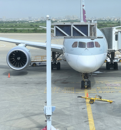 A grey aircraft with the nose pointing at the camera waiting at an airport gate