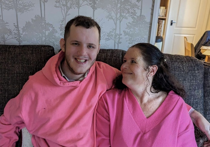 A man and a woman smiling on a sofa wearing pink outfits