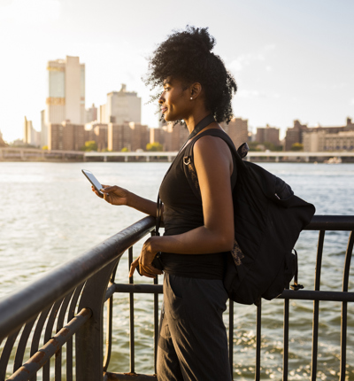 USA, New York City, Brooklyn, woman with cell phone standing at the waterfront