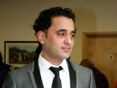 Dilbuhr, a man with dark curly hair wearing a grey suit