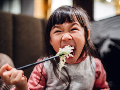 Little girl having meal joyfully with mom