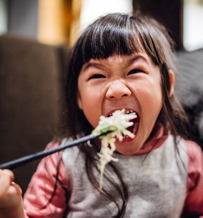 Little girl having meal joyfully with mom