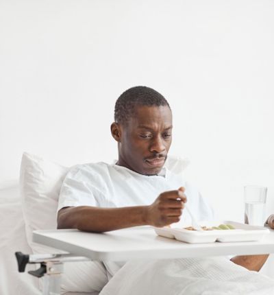 A man in a hospital bed with a tray of food