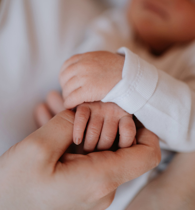 Mother gently holding a baby and touching baby's hand