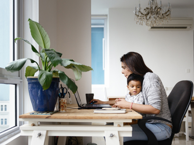 Woman working from a home office desk with her son 598878506