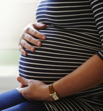 Heavily pregnant woman holding her bump