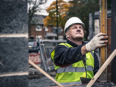 Man with helmet in construction gear building a wall