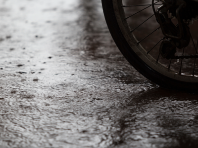 Black and white close-up of a bicycle wheel on a rain-soaked surface