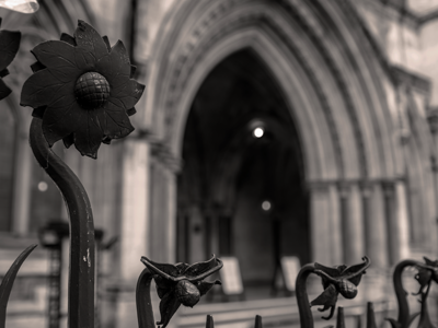 Black-and-white photograph of the Royal Courts of Justice in London, showing a sharply focused decorative wrought-iron fence
