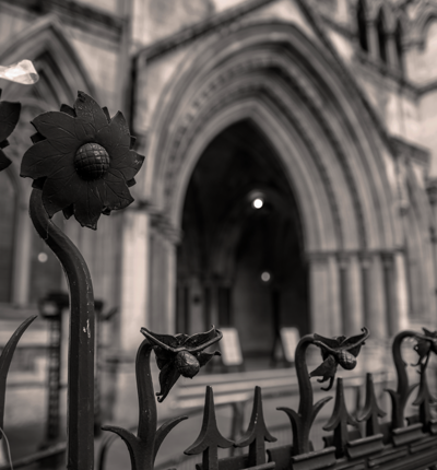 Black-and-white photograph of the Royal Courts of Justice in London, showing a sharply focused decorative wrought-iron fence