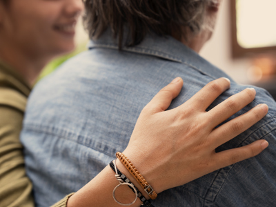 2 People Sitting Closely Together With Hand Resting Gently On The Shoulder
