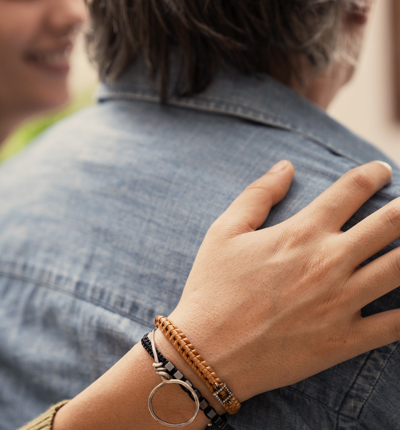 2 People Sitting Closely Together With Hand Resting Gently On The Shoulder