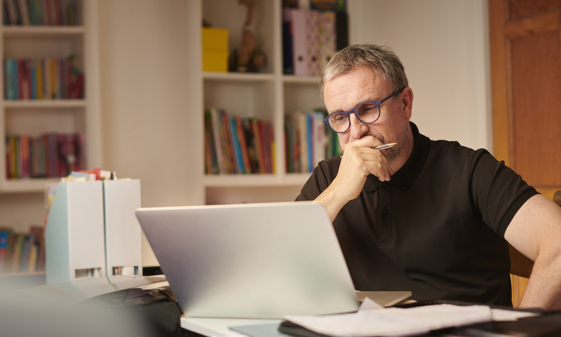 Pensive man at home looking at laptop