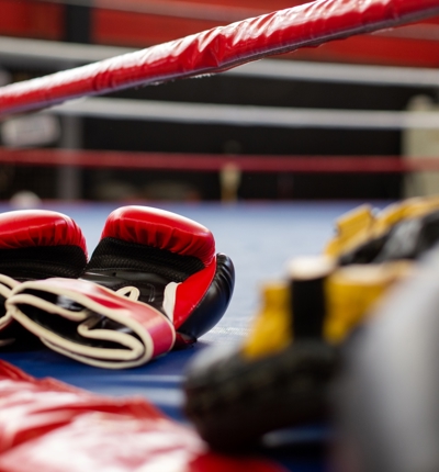 Close up of red boxing gloves on the floor of a boxing ring.