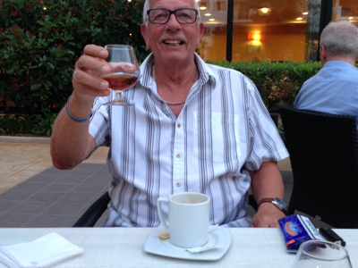 Geoffrey King smiling raising a glass to the camera
