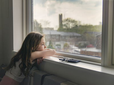 Young girl looking out of window on a rainy day