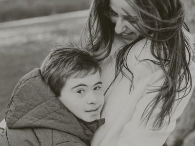 Black and white photo of young boy hugging his mum