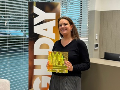 Clare Campbell standing in front of a banner which says Leigh Day, she holds a yellow trophy