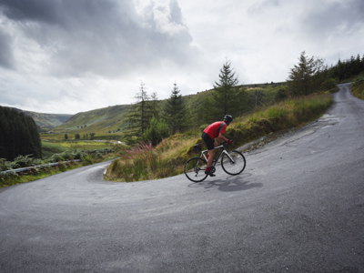 Road cyclist climbing hairpin bends up steep road