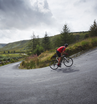 Road cyclist climbing hairpin bends up steep road